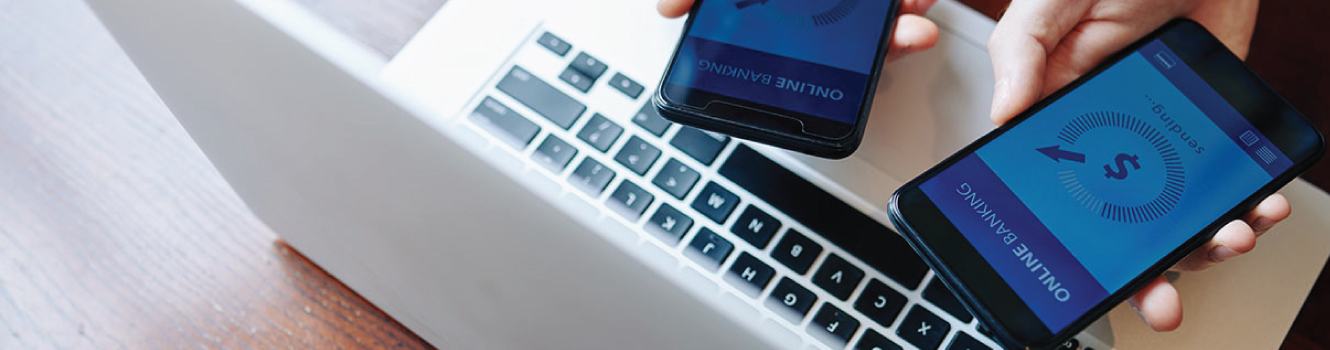 Two hands with two mobile devices on a laptop